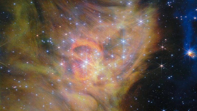 Nébuleuse aux teintes orangées et jaunes parsemée d'étoiles au cœur de l'amas IC 348, observée en infrarouge par le télescope James Webb