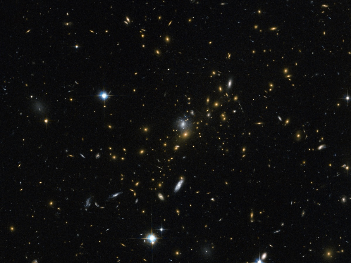Amas de galaxies MACS J0454.1-0300 vu par Hubble, points dorés sur fond noir et galaxies étirées en arcs