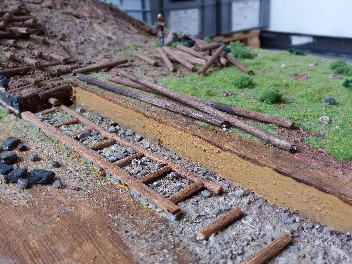 Maquette en coupe d’un rempart gaulois montrant un parement de pierres et des poutres de bois horizontales enfouies dans un remblai