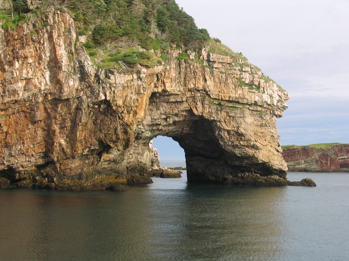 Falaise rocheuse percée d'une arche naturelle au bord de l'eau, sur le littoral de l'ile de Miquelon