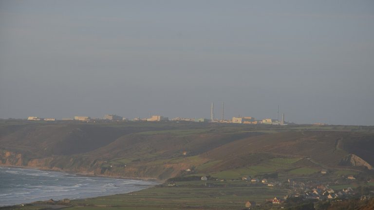 L'usine de retraitement de La Hague sur le plateau du Cotentin, vue de loin au-dessus des falaises, des prairies et de l'anse de Vauville