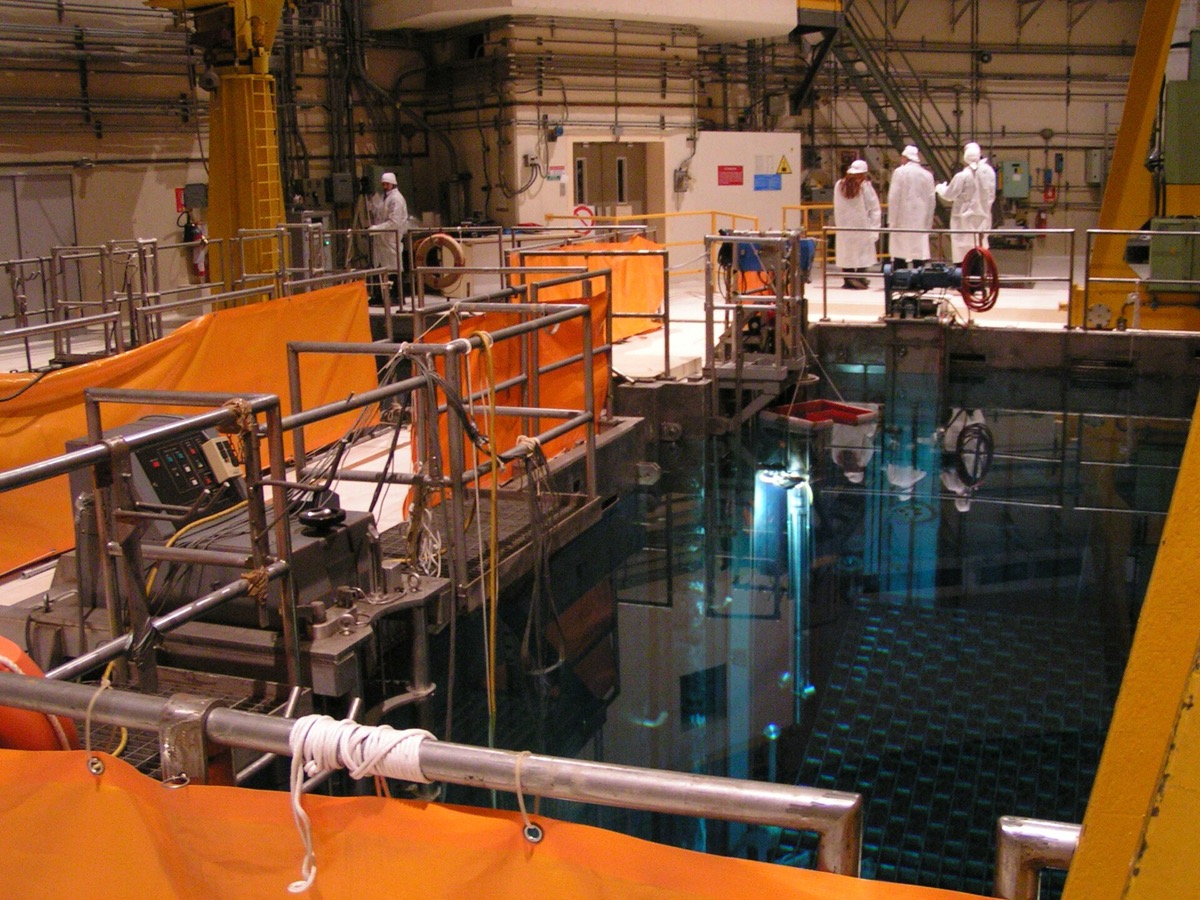 Piscine d'entreposage de combustible usé dans le bâtiment d'une centrale nucléaire, avec passerelles et garde-corps au bord de l'eau