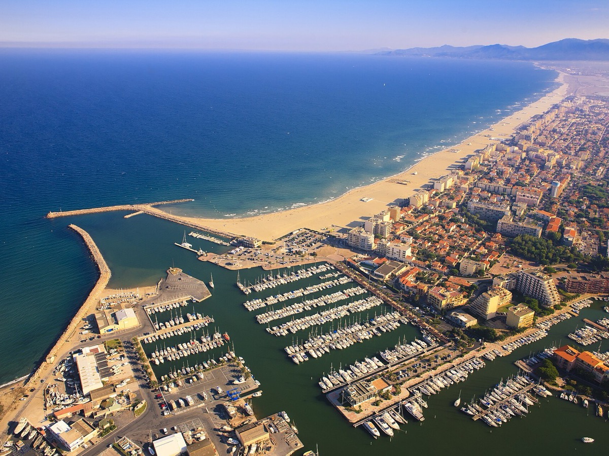 Vue aérienne du port de Canet-en-Roussillon, de sa longue plage de sable et de la ville, avec la mer à gauche et les Pyrénées à l'horizon