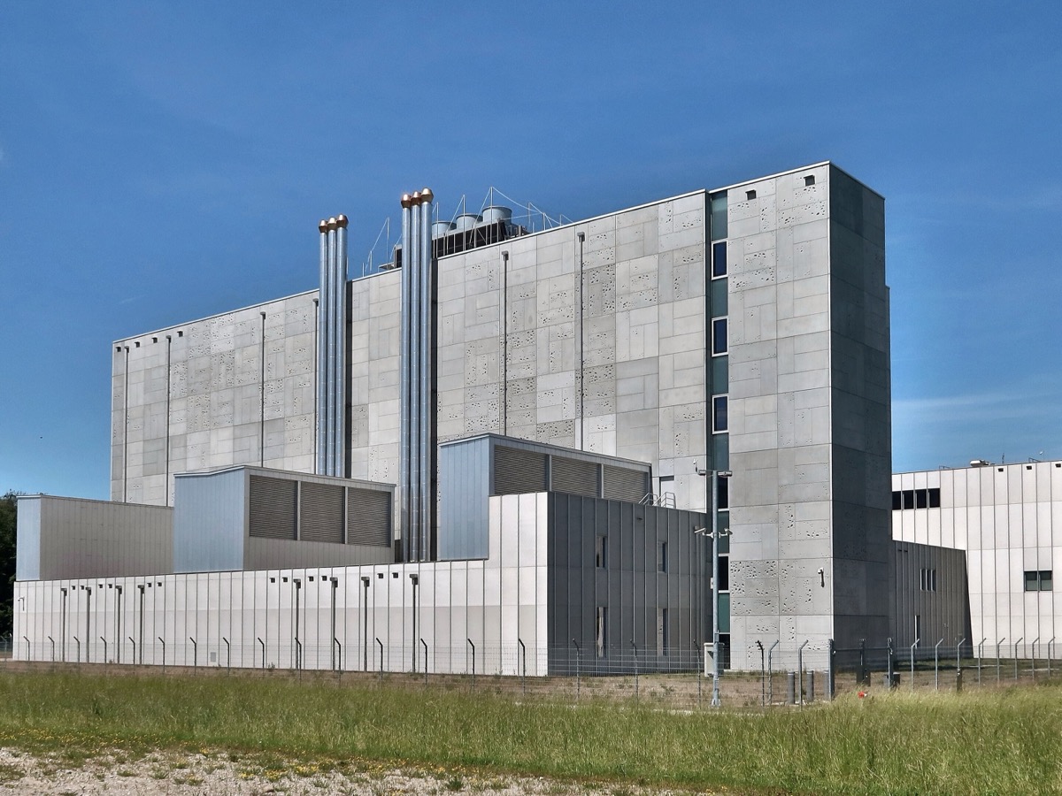 Bâtiment de béton et de tôle d'un centre de données isolé derrière une clôture, avec ses cheminées de ventilation sur le toit