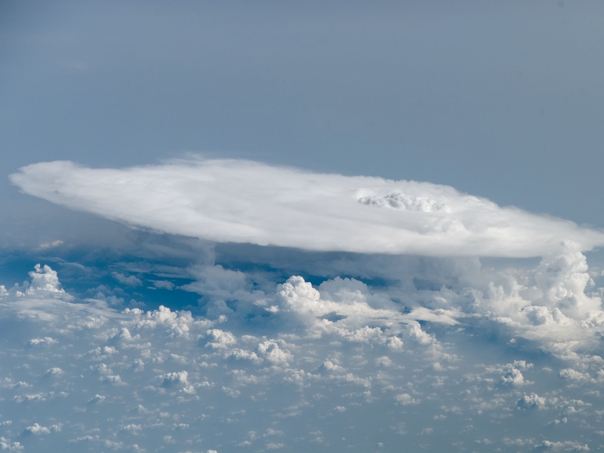Cumulonimbus et son sommet étalé en enclume, photographiés depuis l'orbite au-dessus d'un tapis de nuages