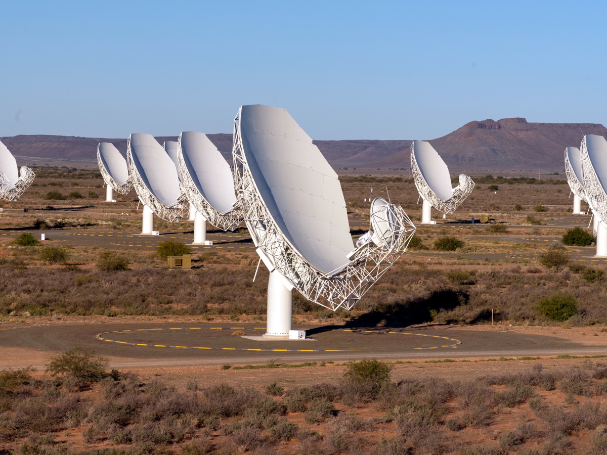 Antennes paraboliques blanches d'un réseau de radiotélescopes alignées dans un paysage semi-désertique