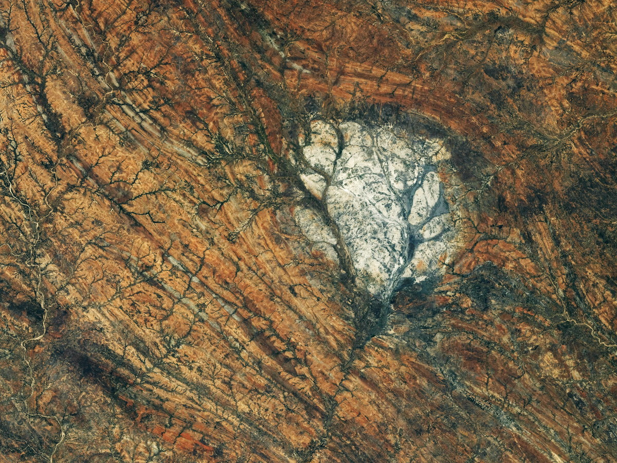 Vue oblique depuis l'orbite d'une tache de roche blanche au milieu d'un relief strié de rouge, dans le sud de Madagascar