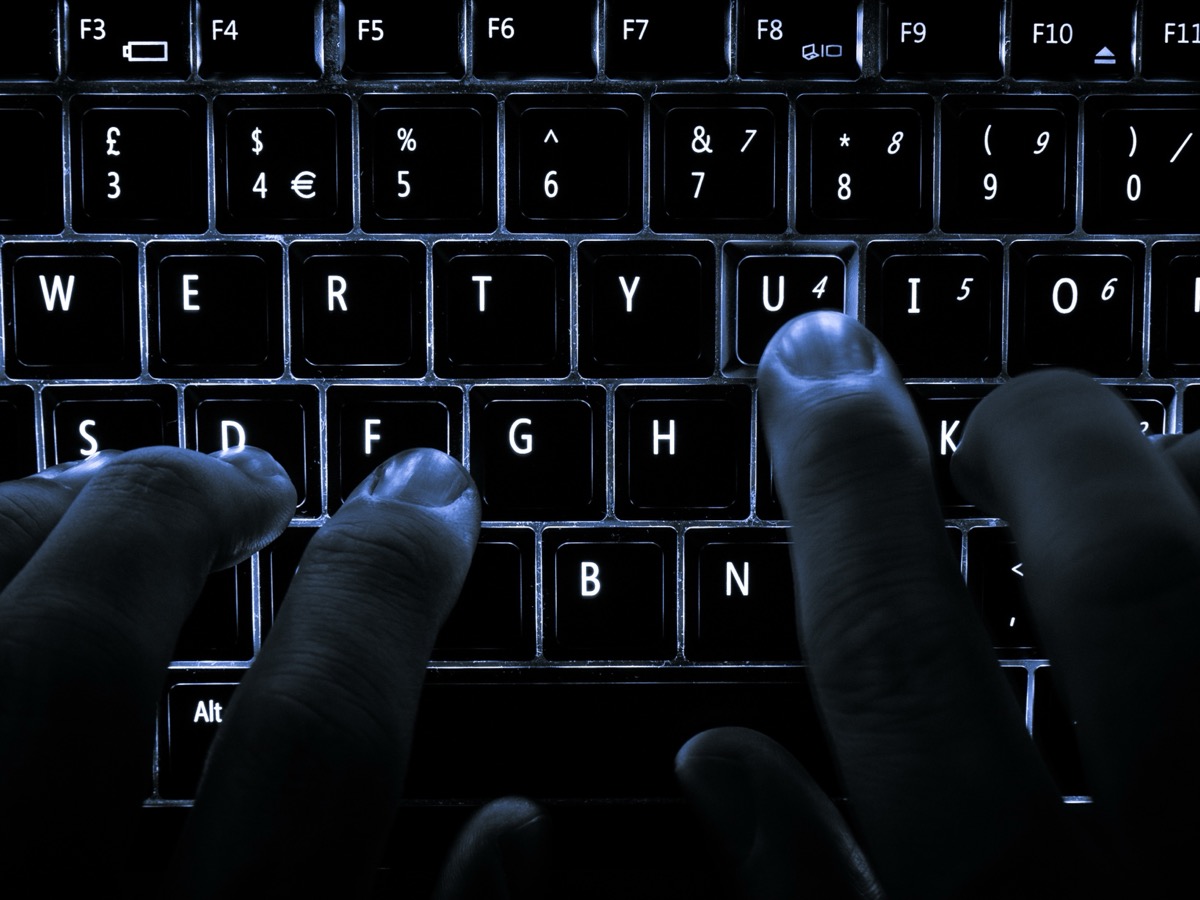 Gros plan sur un clavier d'ordinateur portable rétroéclairé, avec des doigts posés sur les touches