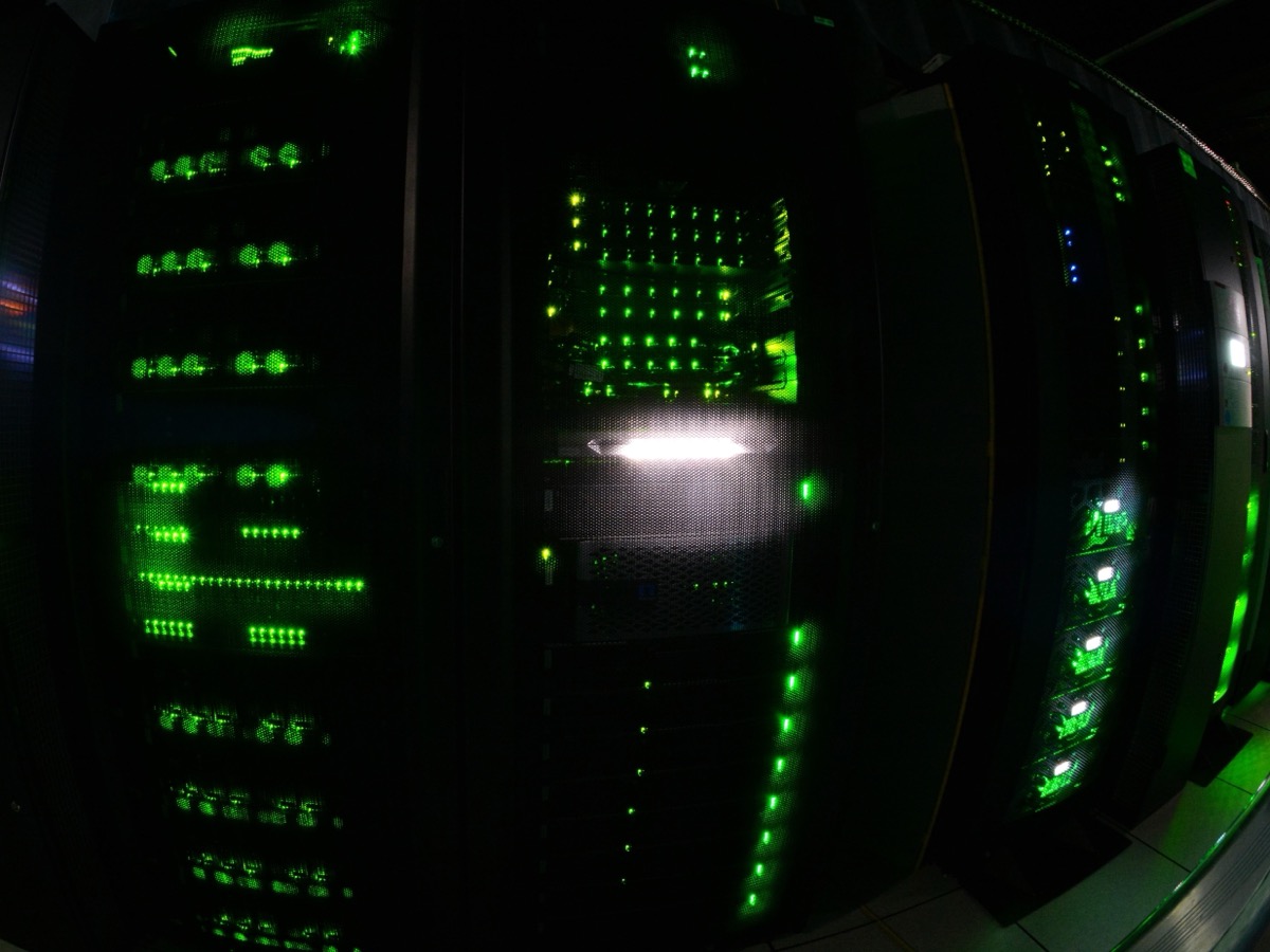 Baies informatiques alignées dans une salle sombre, constellées de voyants verts