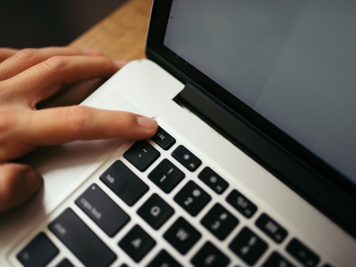Une main posée sur le clavier d'un ordinateur portable, un doigt appuyant sur une touche