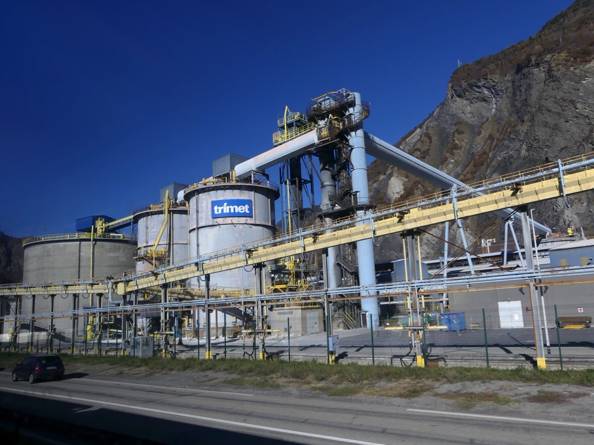 Silos, convoyeurs et tuyauteries d’un site industriel adossé à une paroi rocheuse