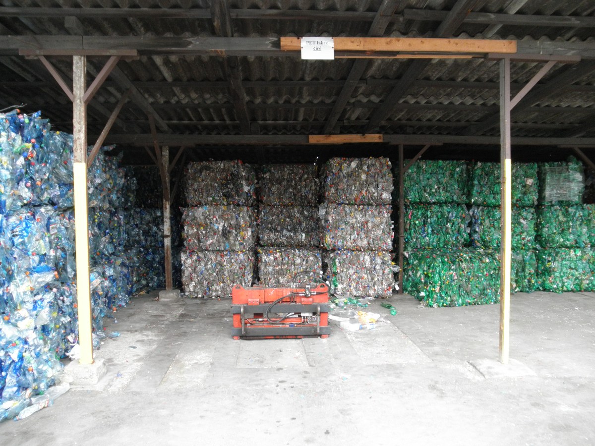 Balles de bouteilles en plastique compressées rangées sous un hangar et triées par couleur, bleu, transparent et vert