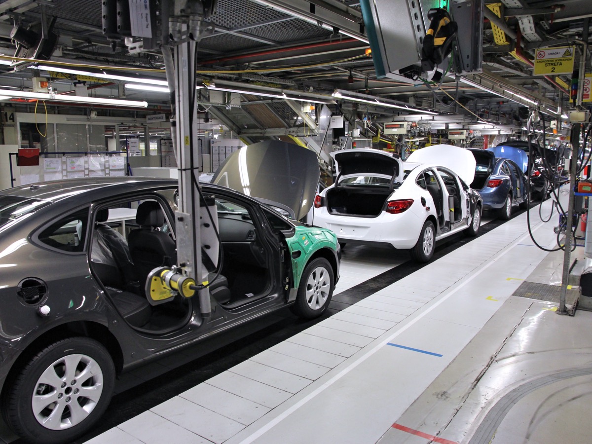 Carrosseries de voitures portes ouvertes alignées sur un convoyeur dans un atelier de montage automobile