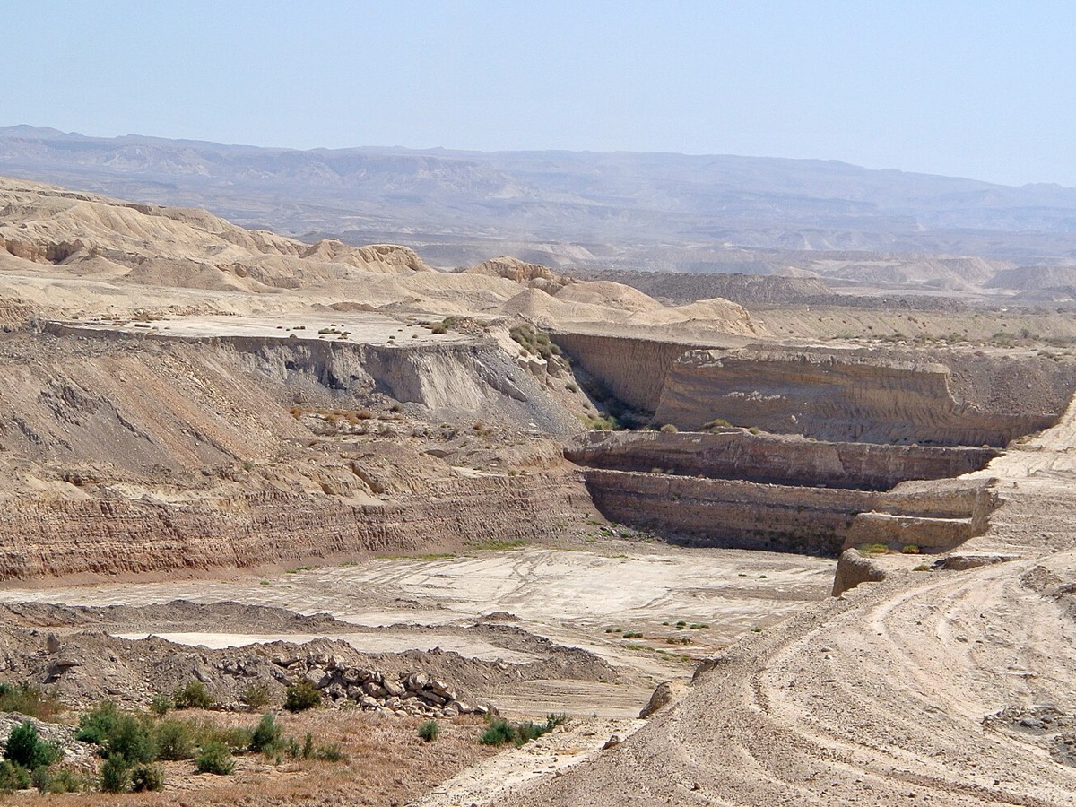 Front de taille d'une mine de phosphorite à ciel ouvert, avec ses gradins et ses pistes dans un paysage désertique