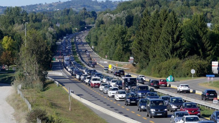 Embouteillage sur deux voies d'autoroute traversant une vallée boisée
