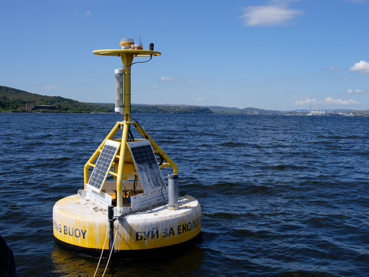 Bouée jaune et blanche équipée de panneaux solaires et d'un mât de capteurs, à la surface de l'eau