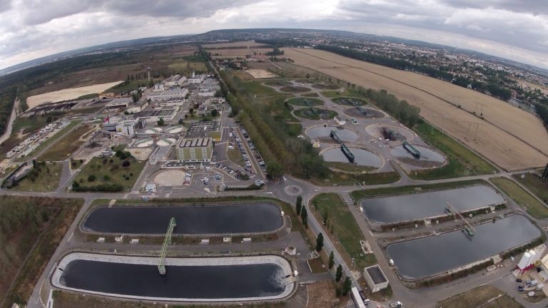 Vue aérienne d'une grande station d'épuration, avec ses bassins rectangulaires et circulaires
