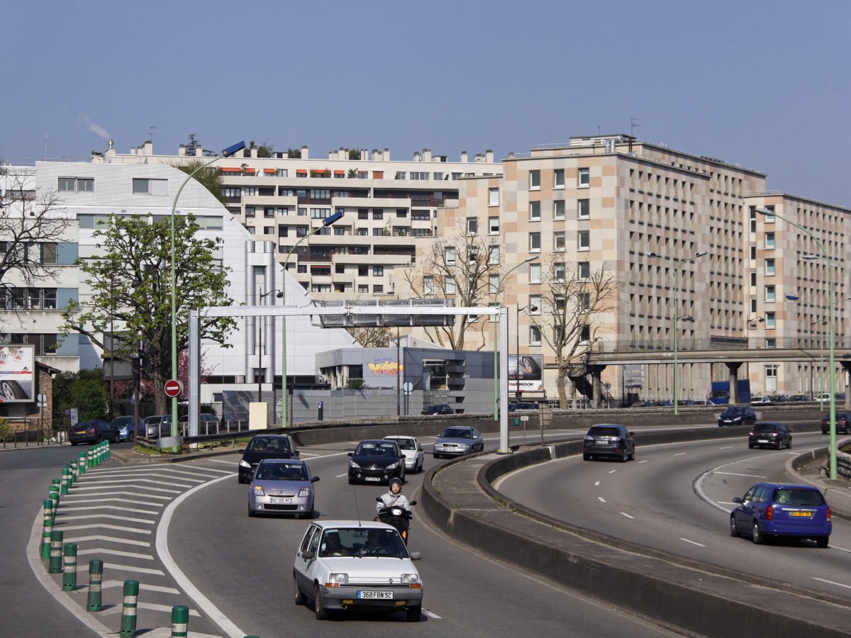 Voitures circulant sur les deux chaussées du boulevard périphérique parisien bordé d'immeubles