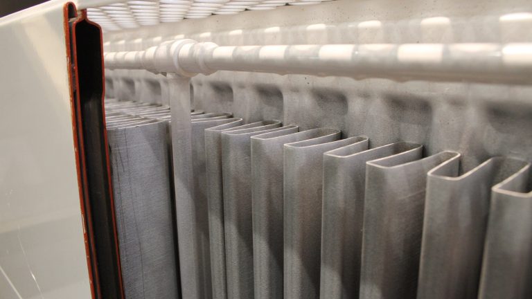Vue en coupe d'un radiateur de chauffage central montrant les lames verticales et le tube de raccordement