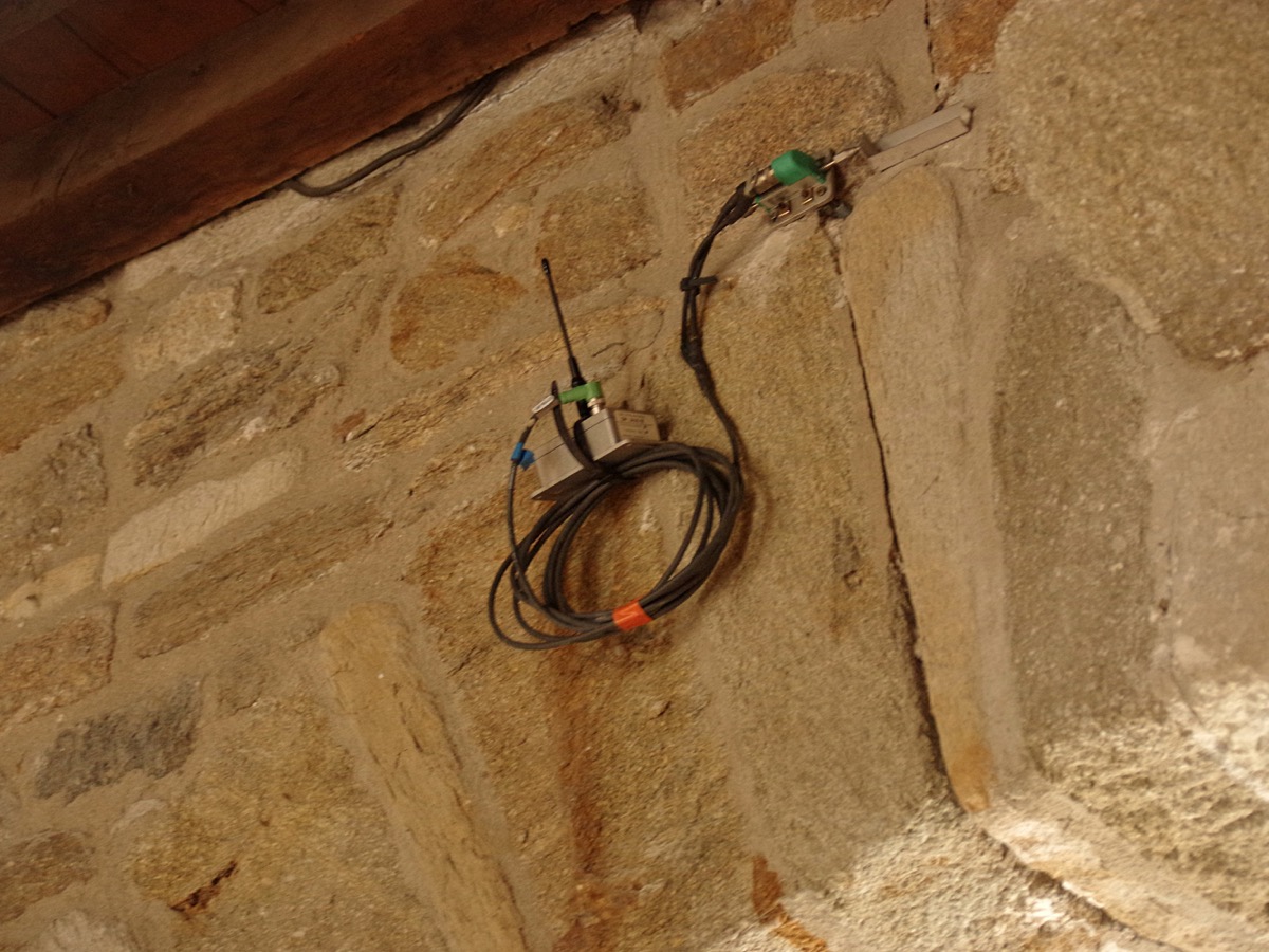 Capteur et câble fixés sur une fissure dans un mur de pierres appareillées