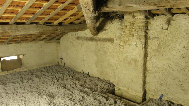 Comble d'une vieille maison dont le plancher est recouvert d'une épaisse couche d'isolant en vrac soufflé