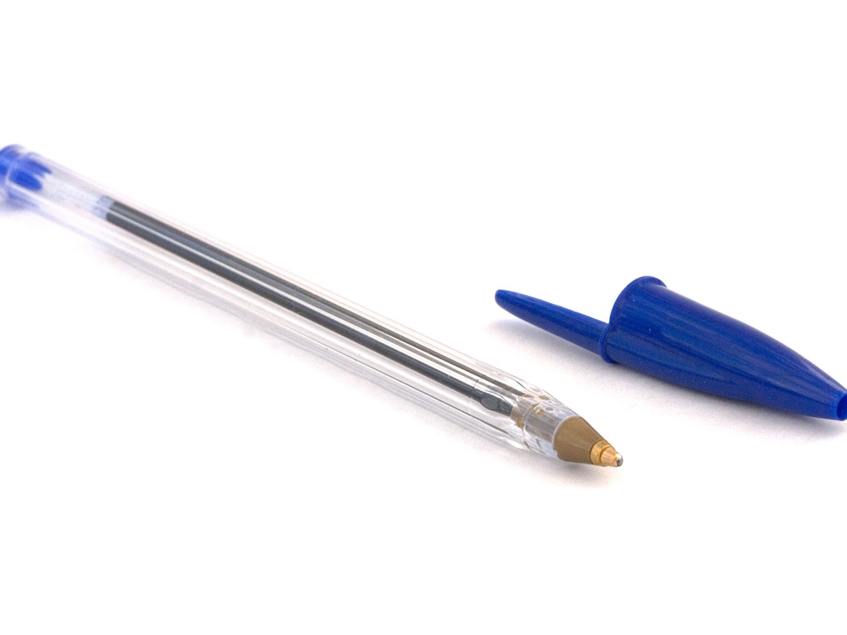 Stylo à bille BIC Cristal bleu au corps transparent hexagonal, capuchon posé à côté, pointe en laiton visible, sur fond blanc