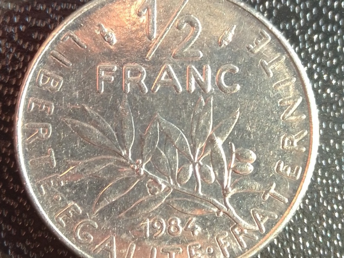 Gros plan sur une pièce d’un demi-franc posée sur un tissu sombre, la valeur et le millésime lisibles