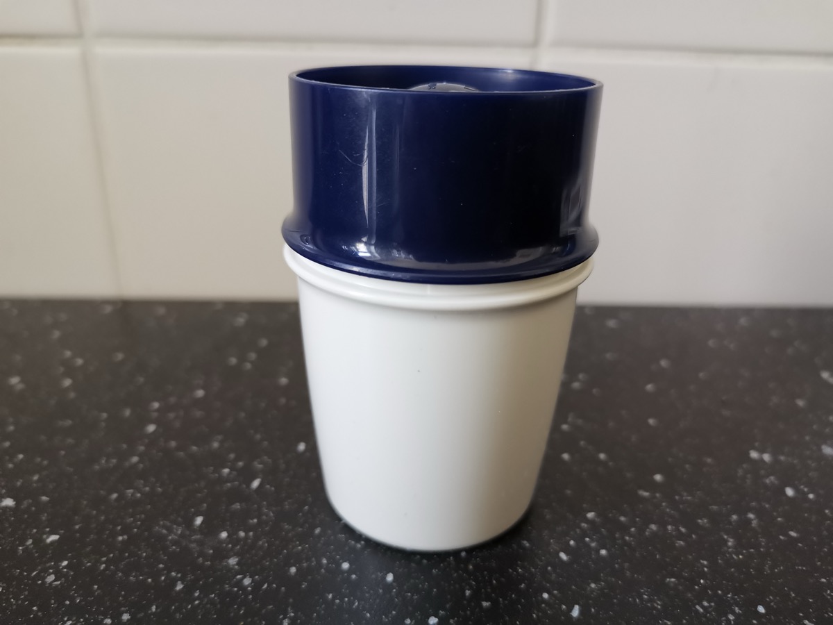 Boîte à œuf Tupperware en deux parties, godet bleu marine emboîté sur un pot blanc, posée sur un plan de travail