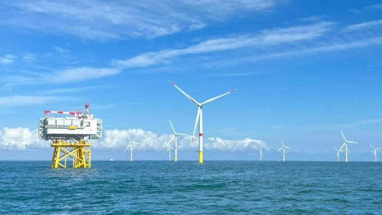 Éoliennes et sous-station électrique du parc éolien en mer de Saint-Nazaire sous un ciel bleu