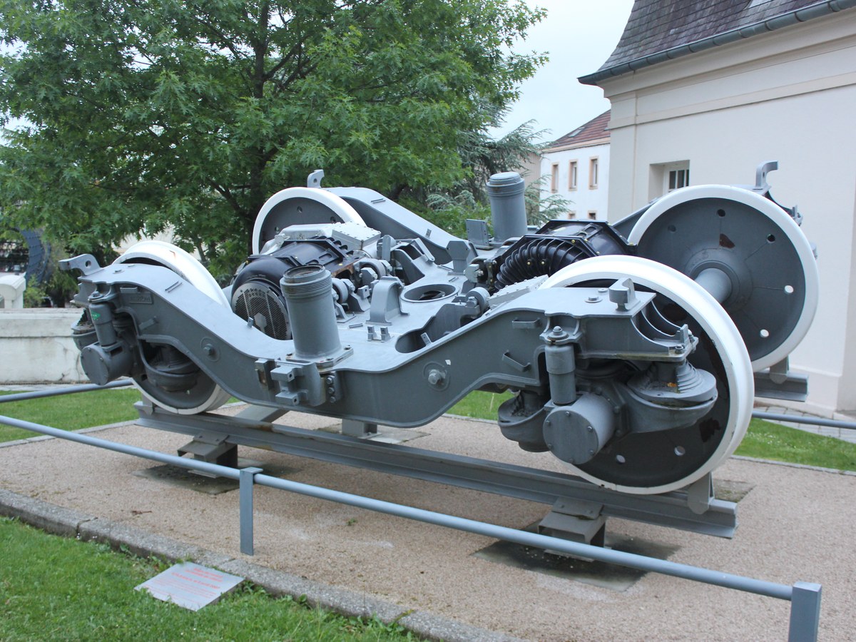 Un bogie moteur gris à deux essieux exposé en plein air au Creusot