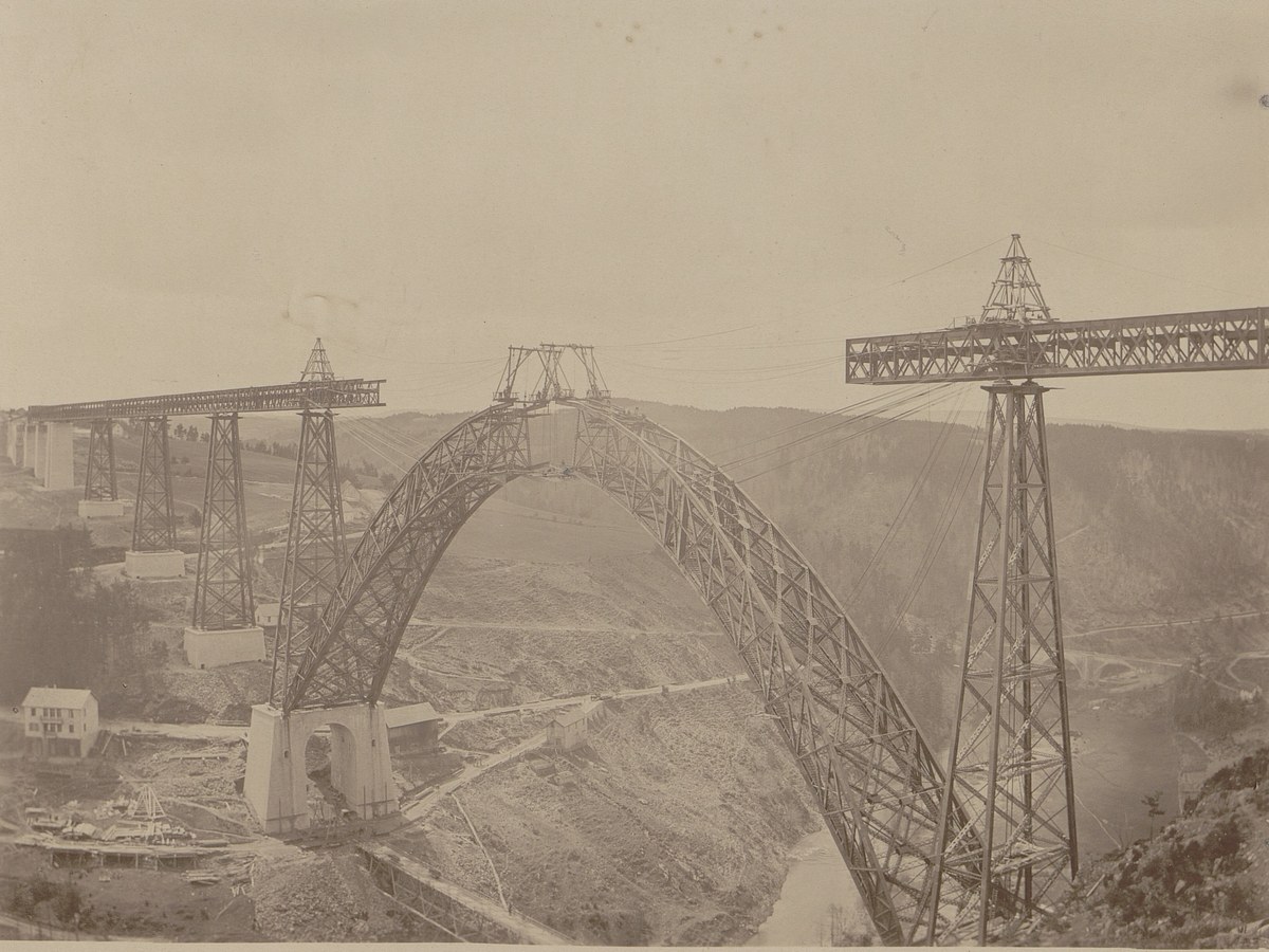 Photographie de 1884 montrant l'arche du viaduc de Garabit presque fermée, montée en porte-à-faux entre deux piles